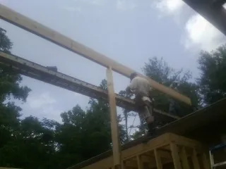 Carpenter setting a ridge beam over a new addition frame — Ice Dam Removal by Roofing Brothers in Bastrop
